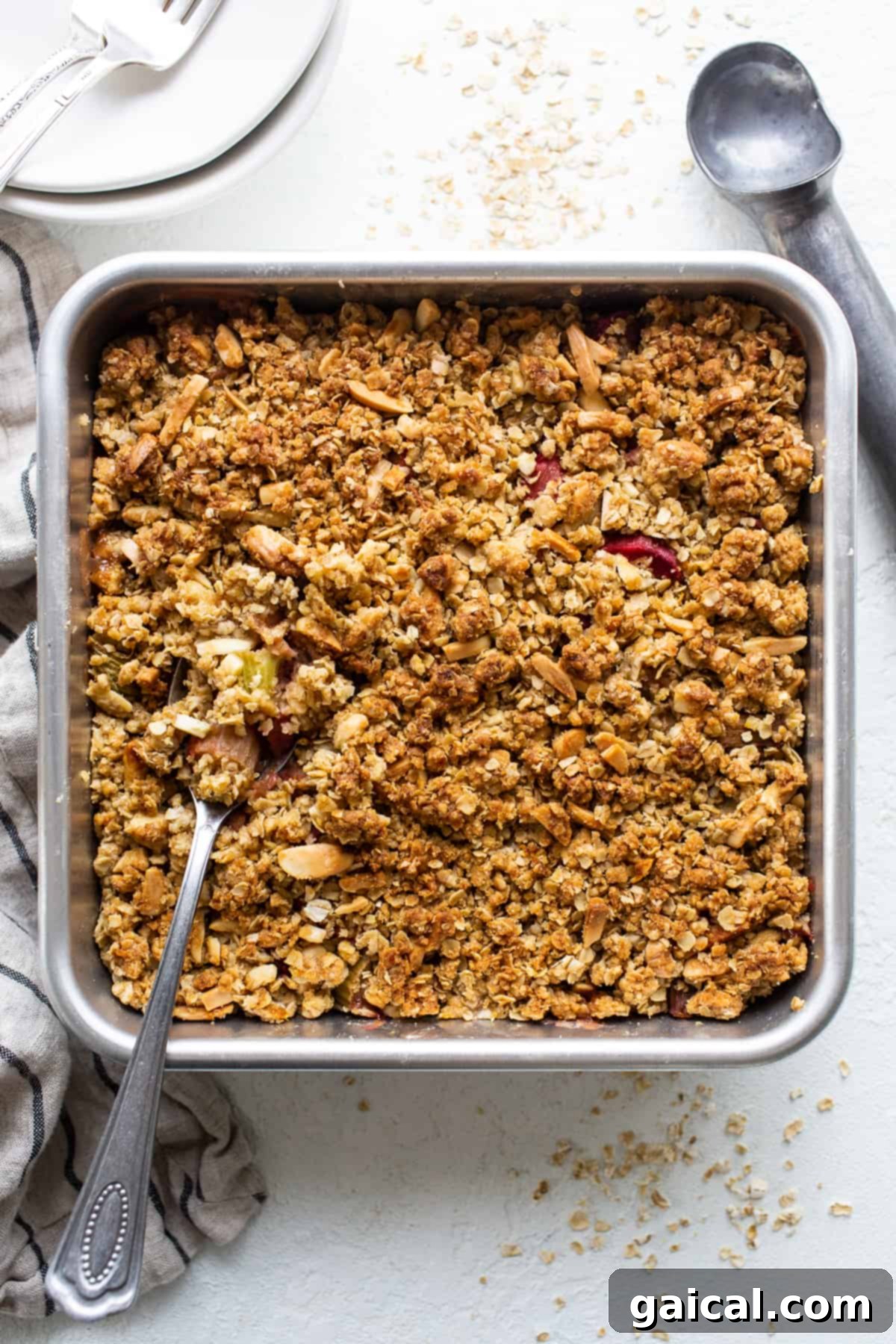 A golden-brown rhubarb crisp fresh out of the oven, bubbling along the edges in a glass baking dish, ready to cool.