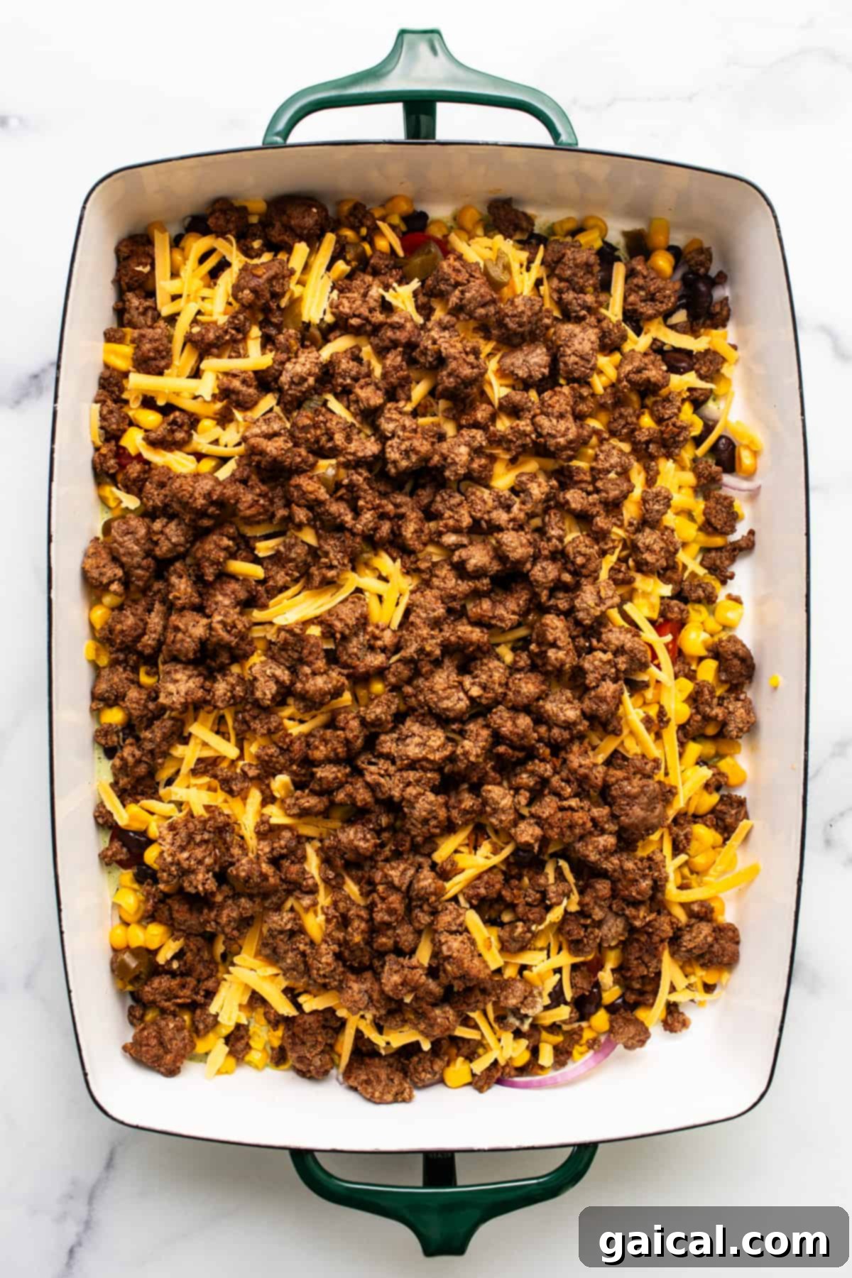 Meal Prep Taco Salad 5 A baking dish with layers of ground beef, corn, and shredded cheese.