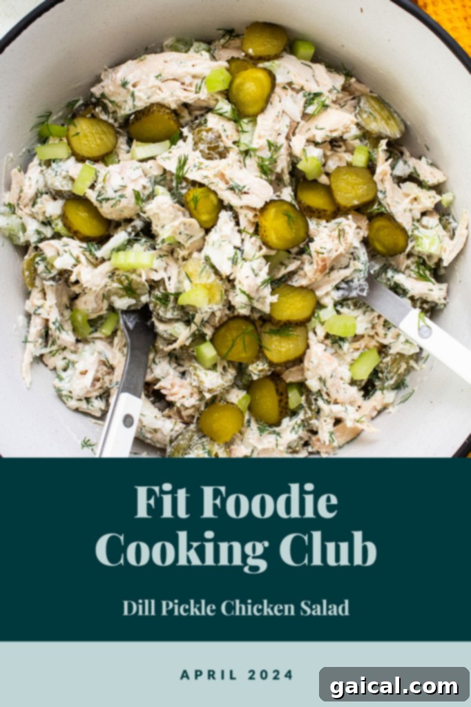 A beautifully presented bowl of creamy dill pickle chicken salad, garnished with fresh dill and thinly sliced pickles, perfectly set for serving. This exquisite dish is the highlight of the Fit Foodie Cooking Club's challenge for April 2024, inviting all home cooks to participate.