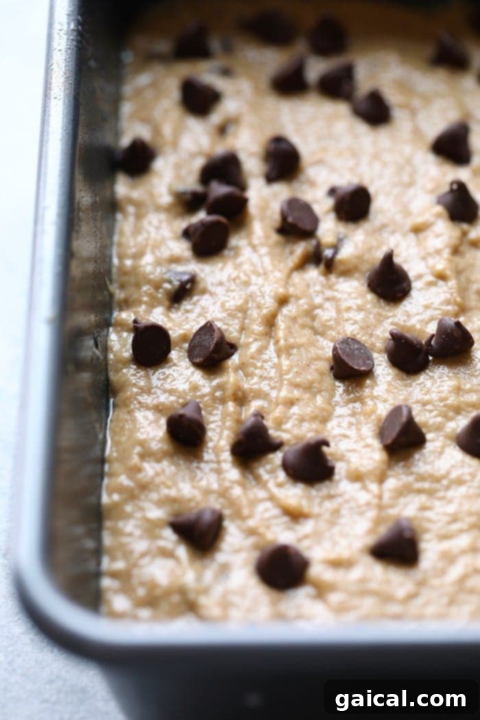 Try our healthy banana bread recipe made with coconut oil for a lightened-up banana bread recipe! Banana bread batter being poured into a greased loaf tin, ready for baking.