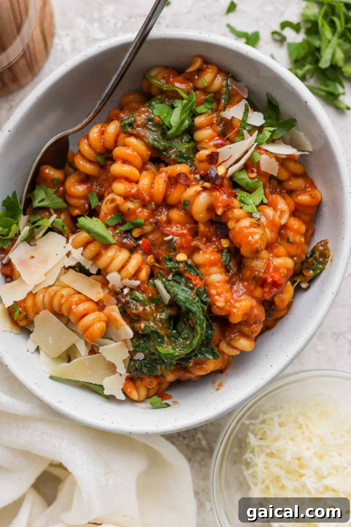 One-Pot Wonder Vodka Pasta 2 A vibrant bowl of creamy tomato-based pasta alla vodka, generously mixed with fresh spinach and topped with delicate shavings of Parmesan cheese.