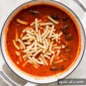 One-Pot Wonder Vodka Pasta 9 A pot of tomato sauce with rigatoni pasta added, simmering gently on a kitchen counter.