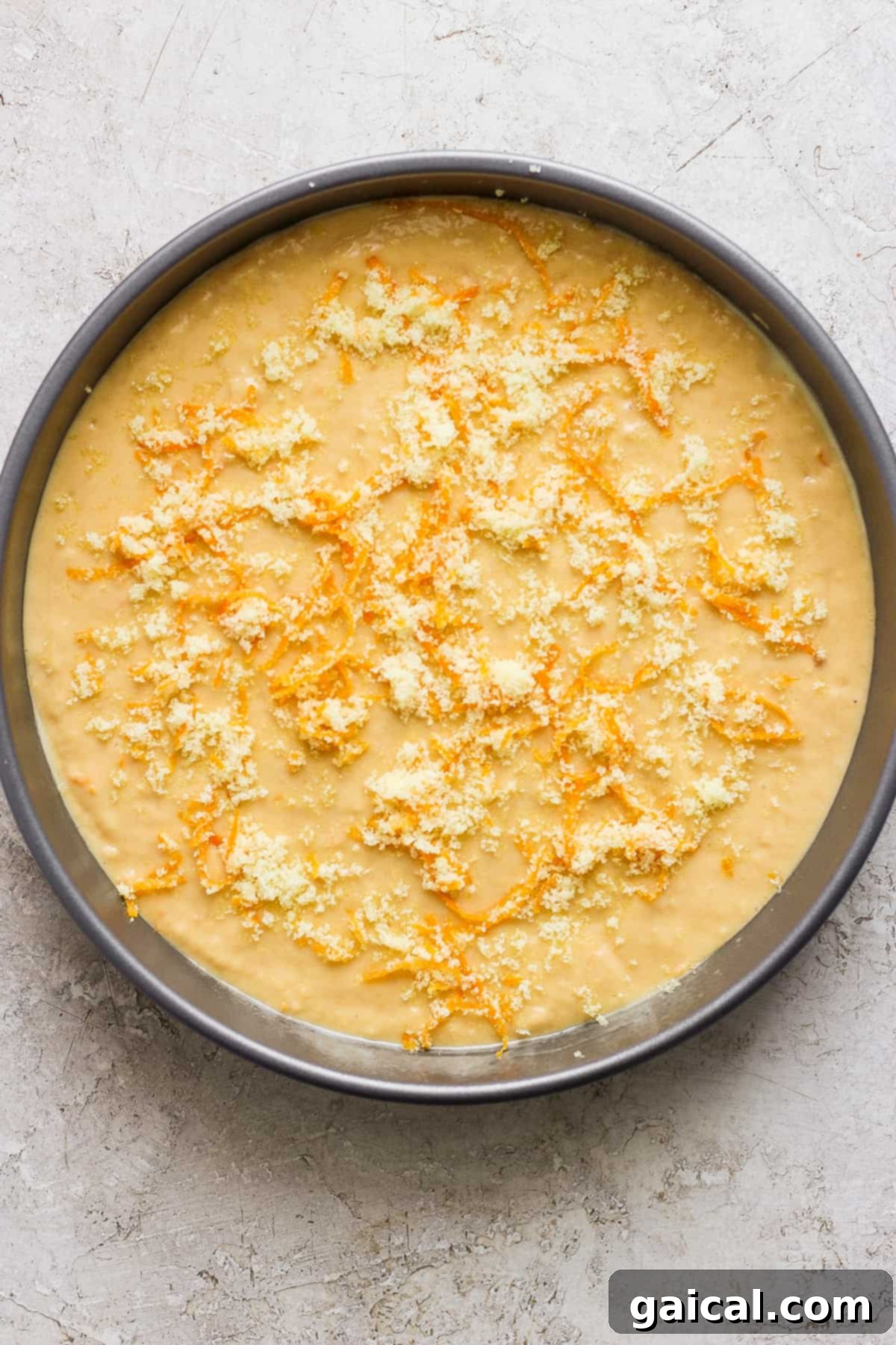The unbaked batter for the orange olive oil cake, rich and smooth, waiting to be transformed in a round baking pan, topped with bright orange zest sugar.