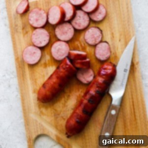 Freshly cooked bratwurst, sliced into neat rounds on a wooden cutting board, with a knife nearby.