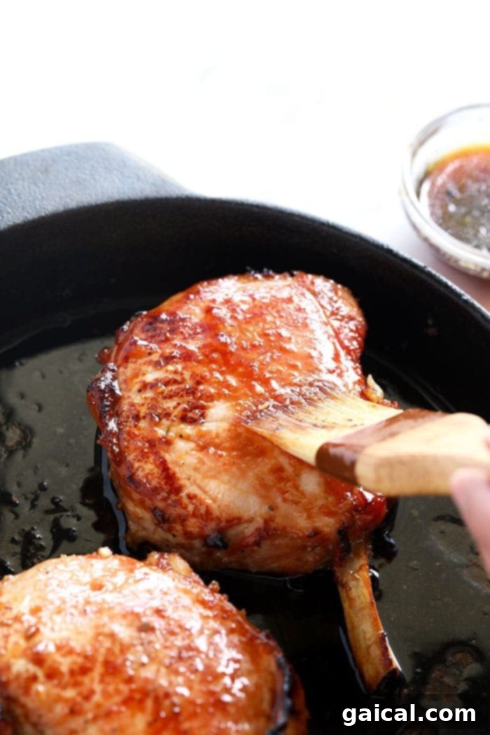 Perfectly seared bone-in pork chops in a cast iron skillet, ready for baking