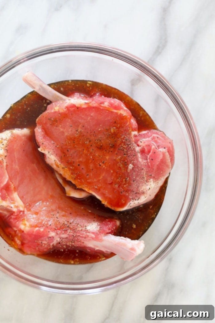 Close-up of pork chops soaking in a flavorful lemongrass ginger marinade in a glass bowl