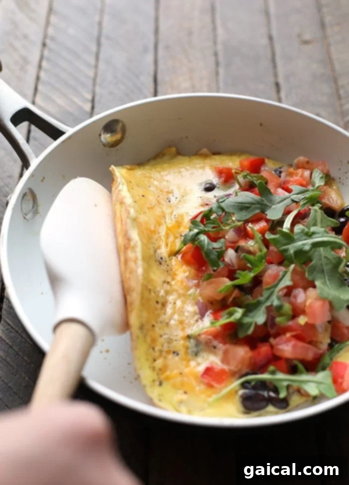 Garden Fresh Omelet 4 A skilled hand gently folding a golden-brown veggie omelette in a non-stick skillet, demonstrating the critical step to a perfectly prepared breakfast.