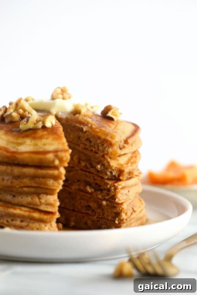 Sweet Potato Power Pancakes 2 A beautifully stacked plate of golden-brown sweet potato pancakes, drizzled with maple syrup.