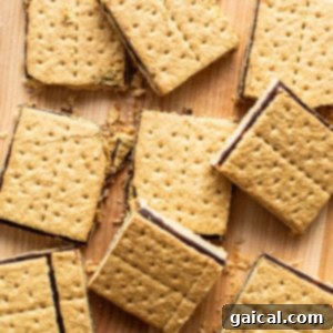 S'mores bars with a gooey chocolate topping and creamy filling, scattered on a wooden surface.
