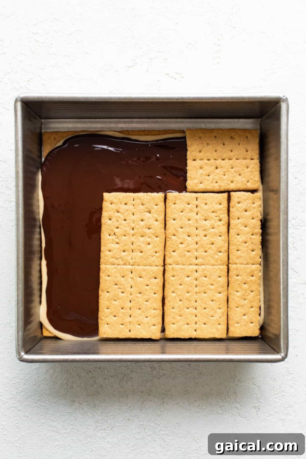 Peanut Butter Protein Smores Freeze 5 A baking dish with a glossy layer of melted chocolate topped by perfectly aligned graham crackers, ready for chilling.