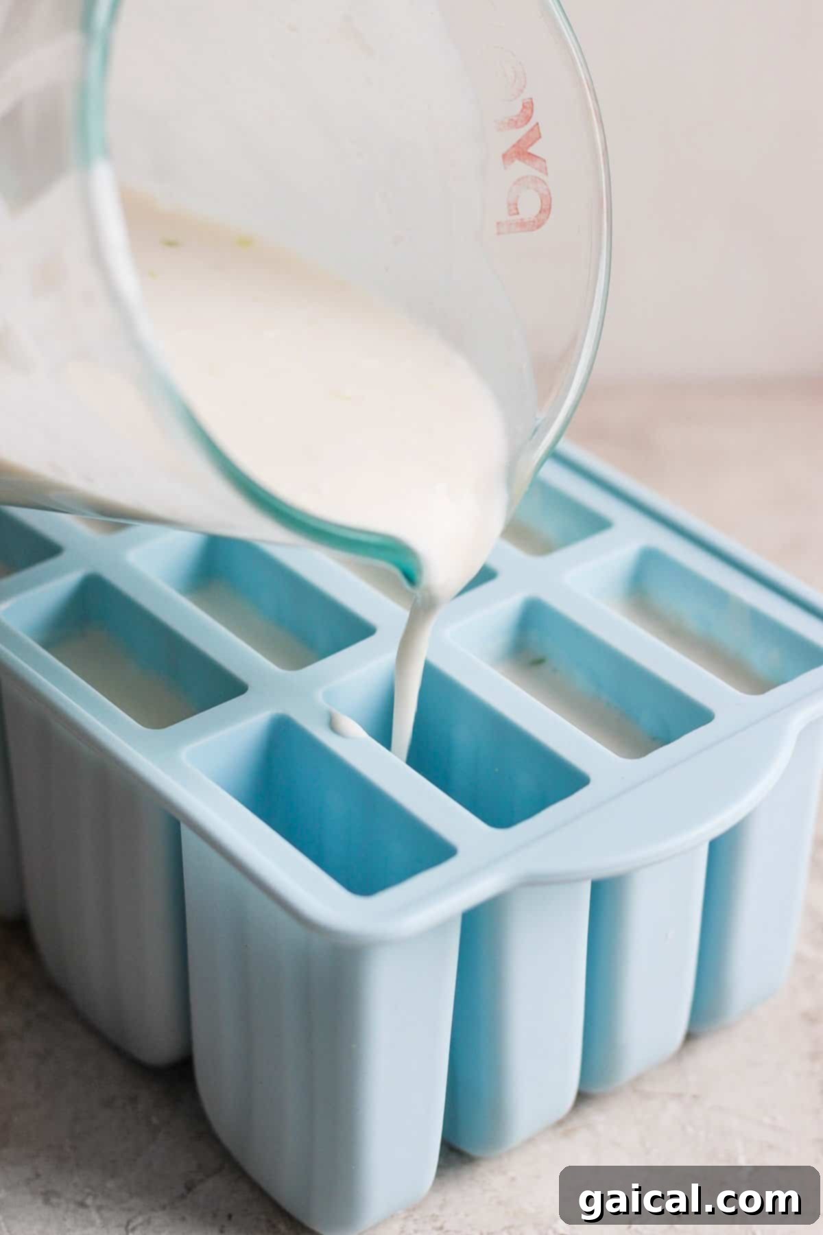 Zesty Coconut Key Lime Frozen Treats 3 A close-up of the coconut cream mixture being poured into popsicle molds, showing the liquid texture before freezing.
