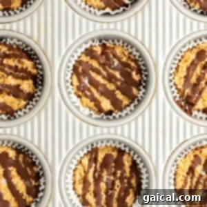 A baking sheet with nine muffin tin liners filled with a mixture topped with drizzled chocolate.