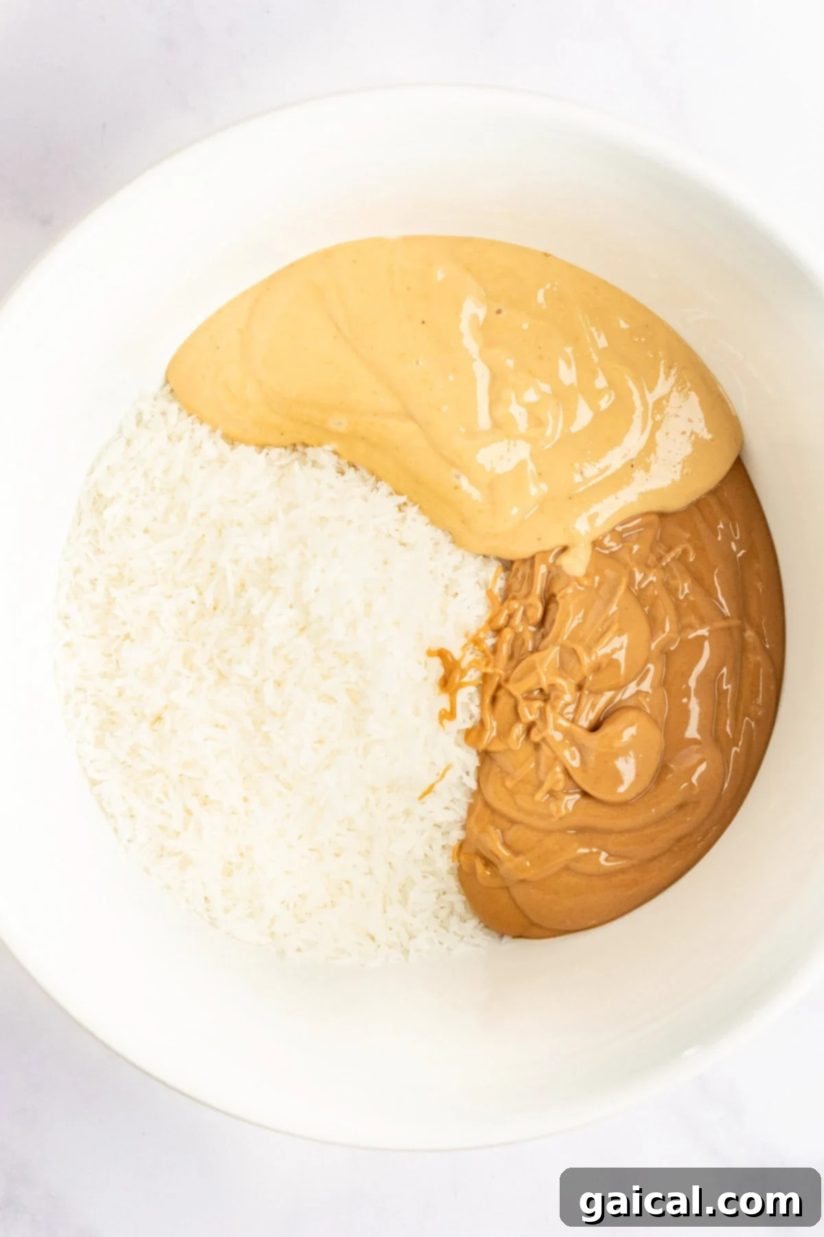 A bowl containing shredded coconut, smooth peanut butter, and crunchy peanut butter.