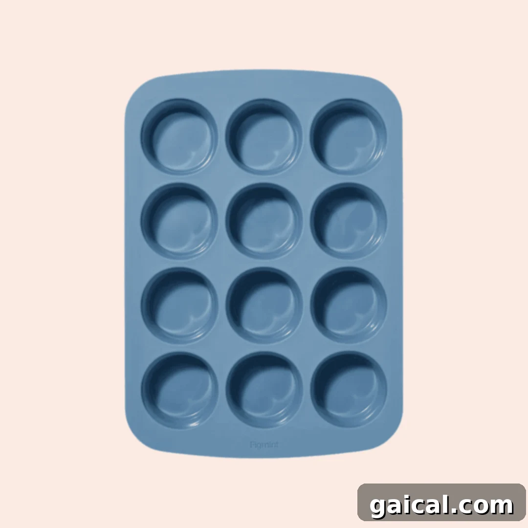 A blue silicone muffin tray with twelve round molds arranged in a three-by-four grid against a light background.