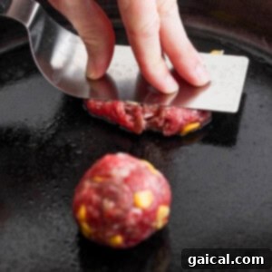 Confetti Corn Smash Burger 9 A person flattening a ball of ground meat on a skillet to form a patty, demonstrating the smash burger technique.