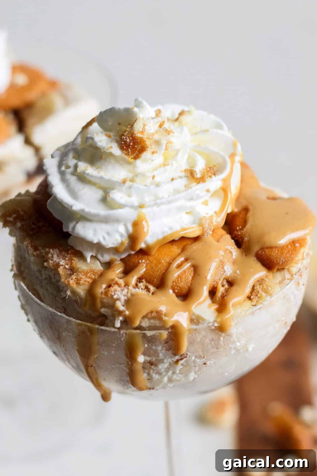Creamy Peanut Butter Banana No-Bake Delight 2 A dessert in a glass featuring layers of caramel, ice cream, whipped cream, and crumbled cookies on top, reminiscent of a peanut butter banana ice box cake.