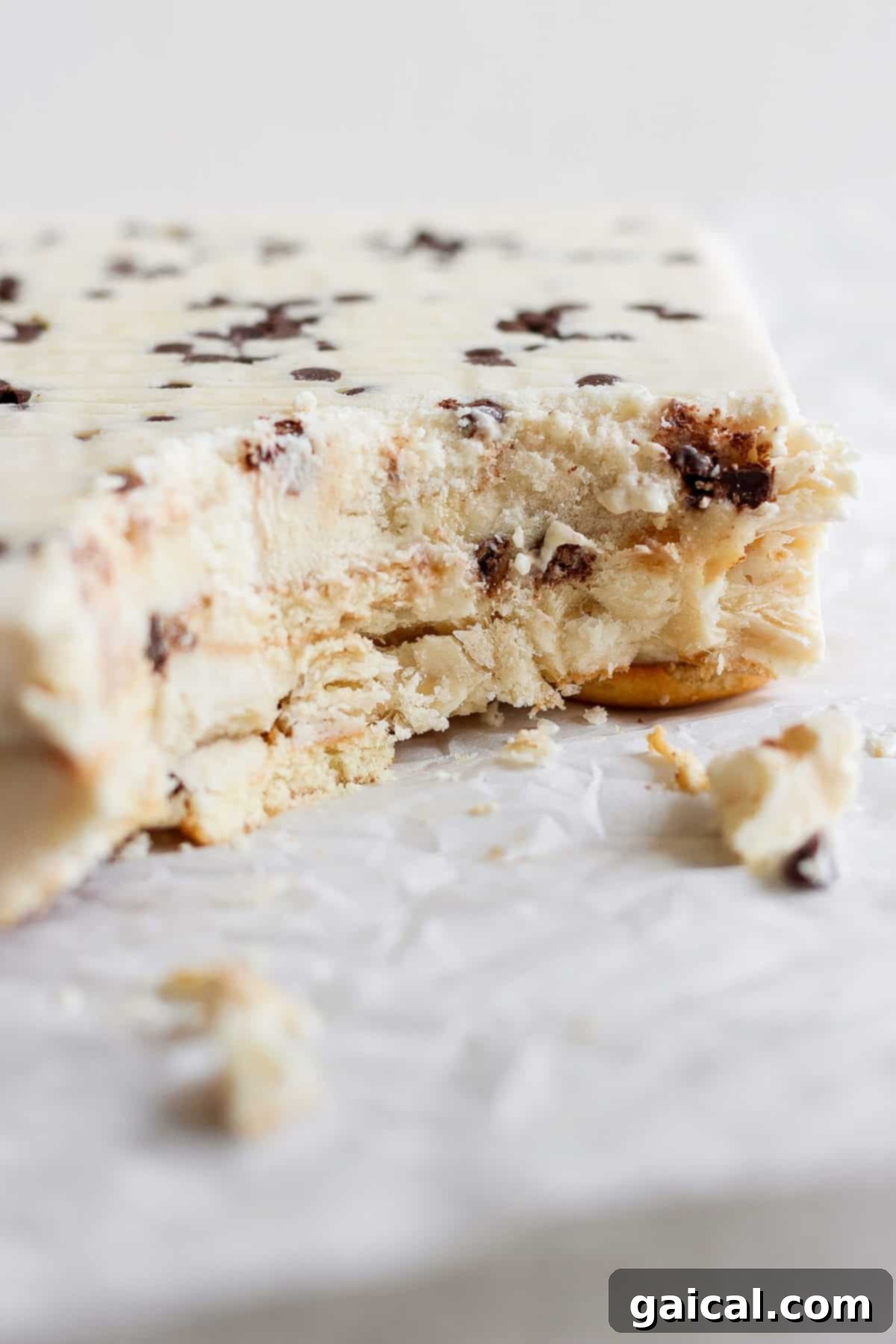 Creamy Peanut Butter Banana No-Bake Delight 5 A partially eaten ice cream cake with chocolate chips and a hint of peanut butter banana lies on white parchment paper.