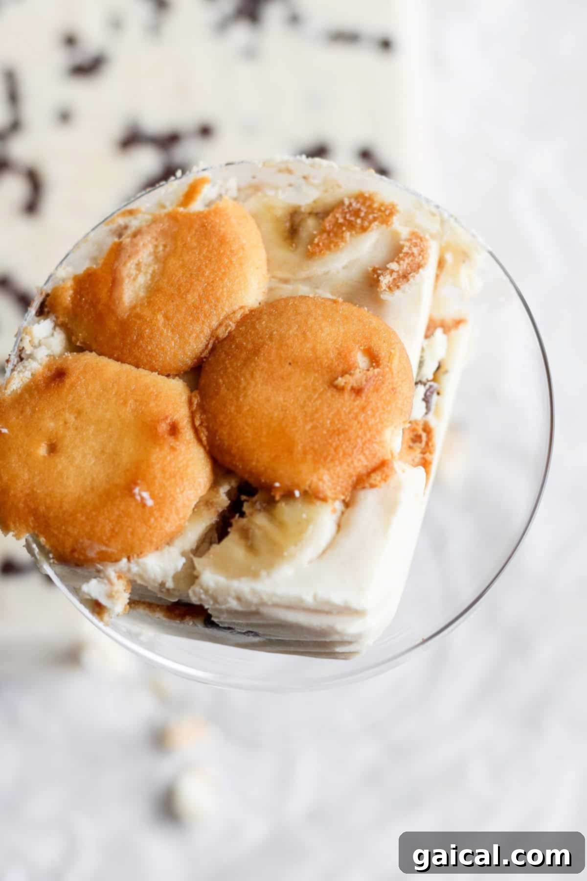 Creamy Peanut Butter Banana No-Bake Delight 6 A glass bowl filled with a dessert made of layered vanilla wafers, slices of banana, and creamy pudding. The dessert, reminiscent of a peanut butter banana ice box cake, is topped with vanilla wafers.