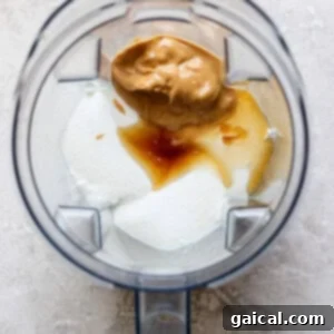 A blender containing yogurt, peanut butter, vanilla extract, and honey viewed from above evokes the creamy richness of a peanut butter banana ice box cake.