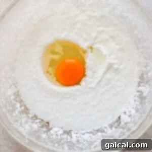 Golden Pineapple Flips 11 An egg being cracked into the wet mixture, with other ingredients already combined.
