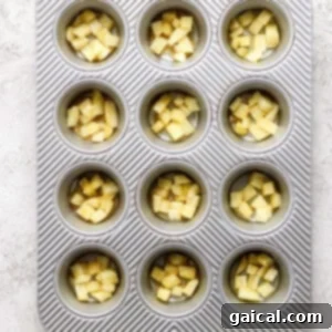 Golden Pineapple Flips 13 A muffin tin containing evenly chopped pineapple chunks mixed with brown sugar in each compartment.
