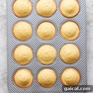 Golden Pineapple Flips 14 Freshly baked muffins in a 12-cup muffin tray with a striped pattern, viewed from above on a light surface.
