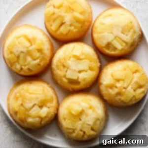 Golden Pineapple Flips 15 Plate of pineapple upside-down mini cakes topped with pineapple chunks on a light textured surface.