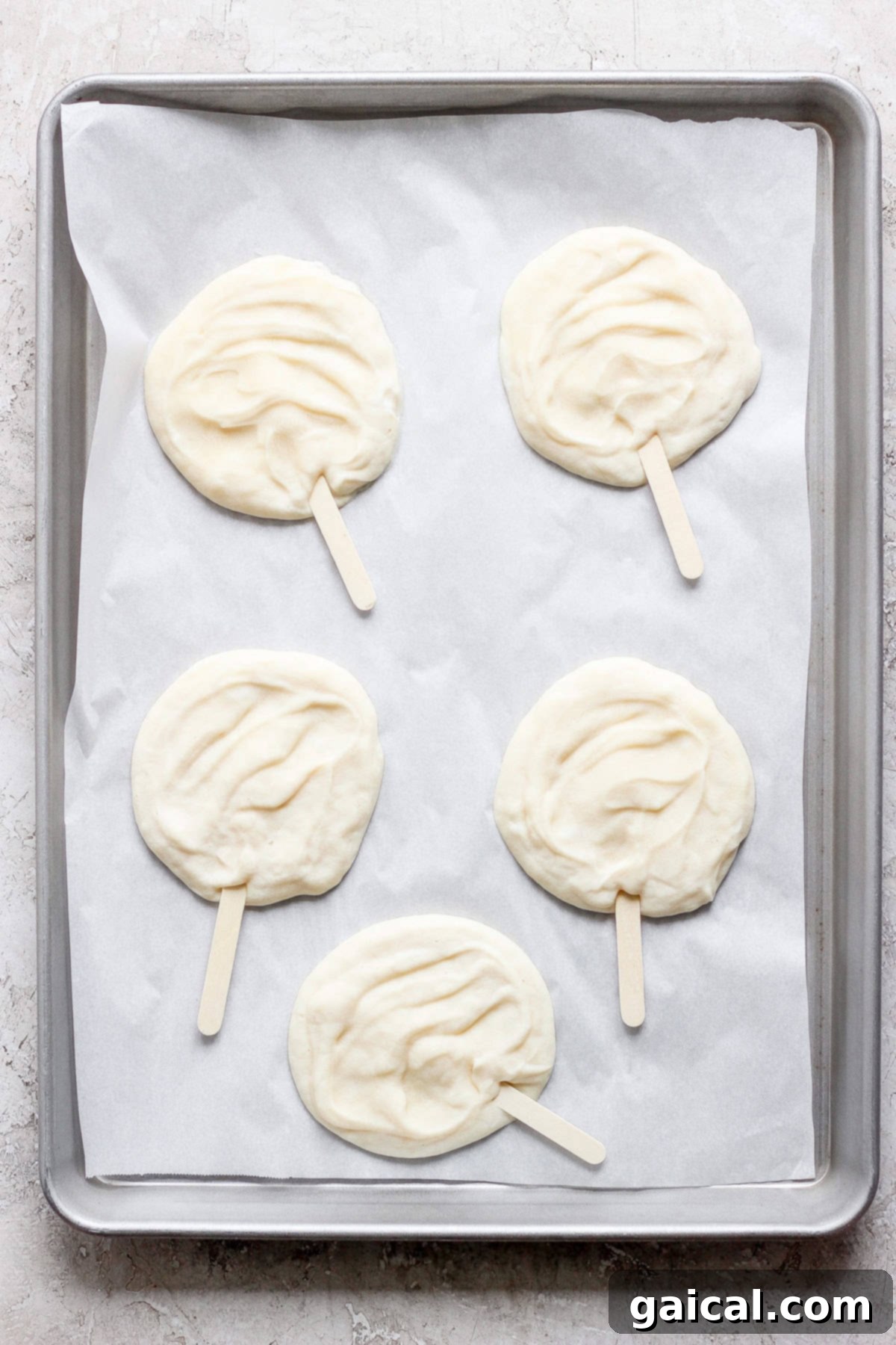Homemade Dilly Delights 3 Four raw popsicle-shaped dough pieces on parchment paper in a gray baking tray.