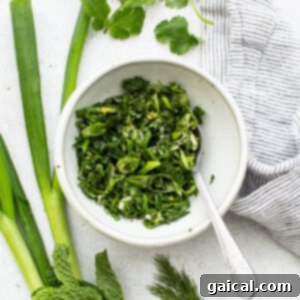 Freshly chopped herbs for gremolata in a bowl, with a spoon for mixing, representing the gremolata preparation.