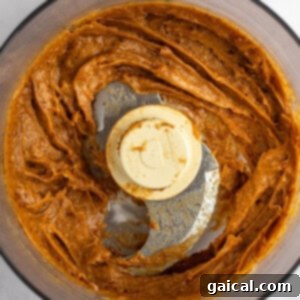 Gooey Cinnamon Apple Rolls 12 A food processor contains a blended brownish-orange mixture with a smooth consistency. The processor's blade and lid cover are visible.