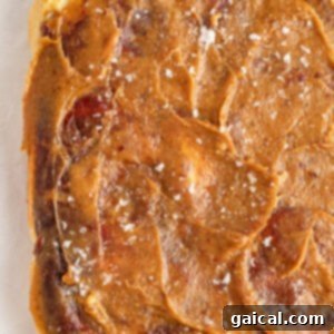 Gooey Cinnamon Apple Rolls 17 A close-up of a square piece of caramel-colored food that appears to be swirled with light and dark streaks and sprinkled with coarse salt on top.