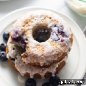 Spiced Orchard Doughnuts 3 A stack of blueberry glazed donuts on a plate.