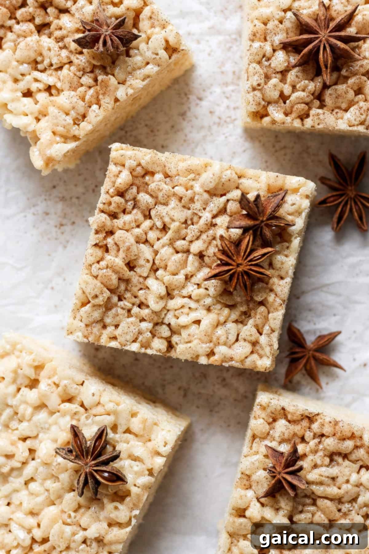 Aromatic Chai & Nutty Brown Butter Crispy Treats 2 Square rice crispy treats with a dusting of spices and garnished with star anise, arranged on a parchment paper surface.