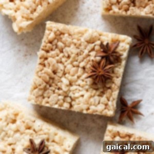 Square rice crispy treats with a dusting of spices and garnished with star anise, arranged on a parchment paper surface.
