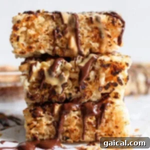 Aromatic Chai & Nutty Brown Butter Crispy Treats 7 Stacked toasted rice krispie treats drizzled with chocolate and caramel sauces on a white surface.