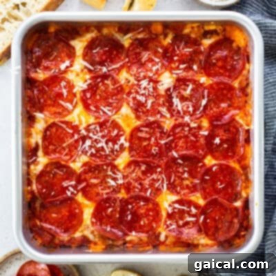 Square pan of pepperoni pizza with a golden crust, melted cheese, and sliced pepperoni, topped with grated cheese, surrounded by bread slices and a striped napkin.