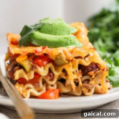 A slice of lasagna topped with avocado slices and garnished with cilantro, served on a white plate with a fork.