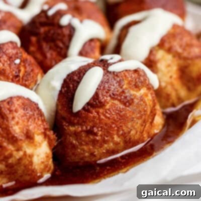 Close-up of cinnamon rolls topped with white icing and glazed with syrup.