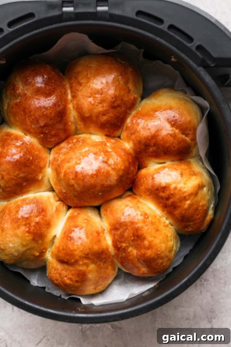 Golden brown rolls arranged in a circular shape inside an air fryer basket, lined with parchment paper.