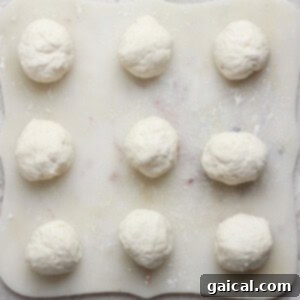 Nine dough balls on a floured surface, arranged in a 3x3 grid.