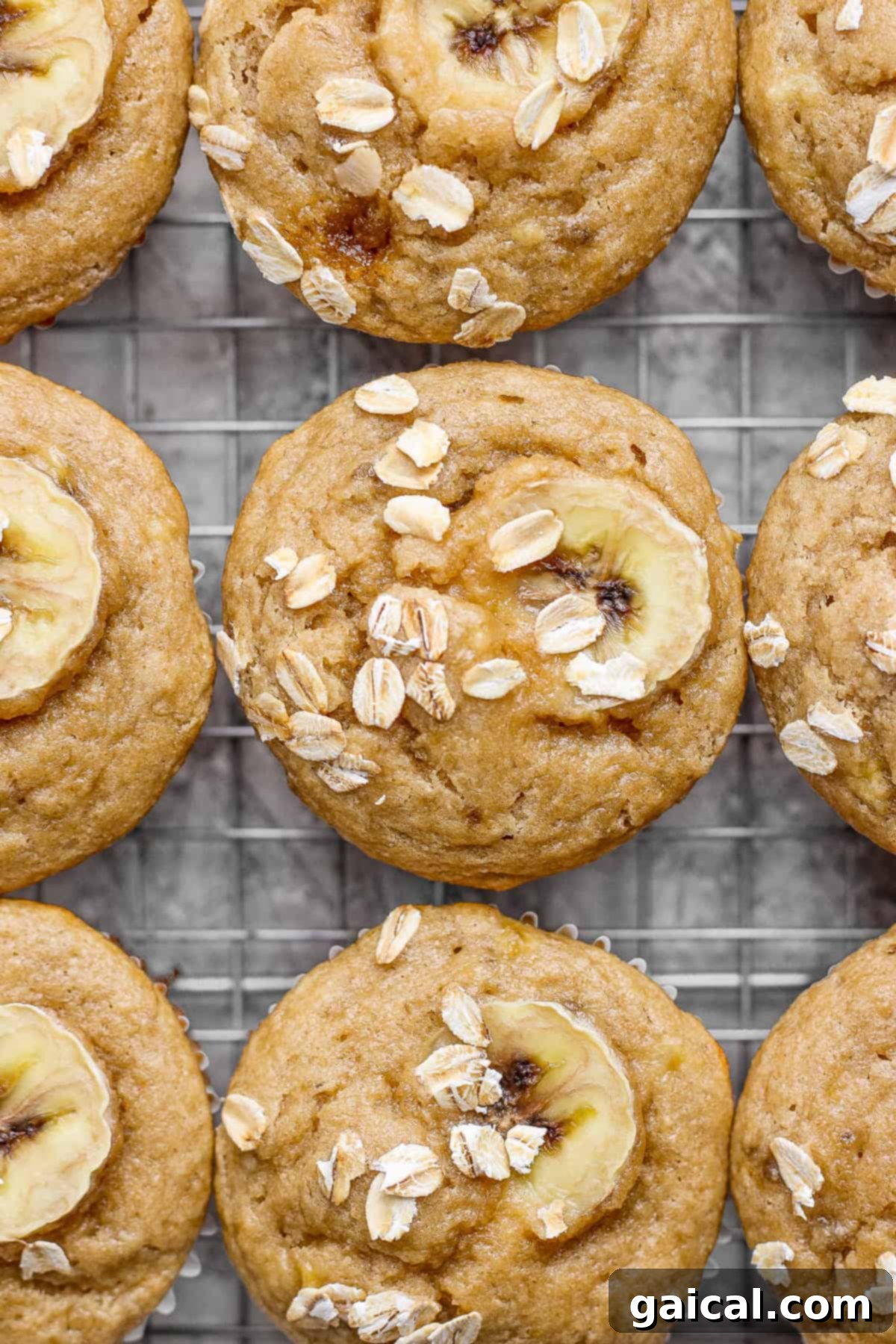 Wholesome Banana Oat Muffins 5 Freshly baked banana oat muffins, garnished with banana slices and oats, cooling on a wire rack.