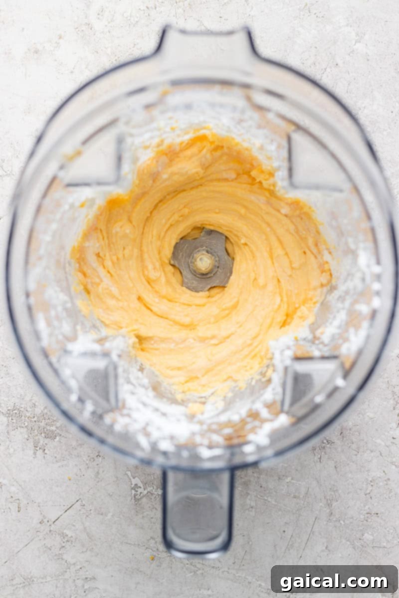Top view of a blender with creamy, whipped mixture inside, surrounded by a dusting of white powder on the container's edges.