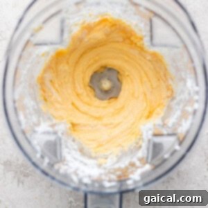 Top view of a blender with creamy, whipped mixture inside, surrounded by a dusting of white powder on the container's edges.