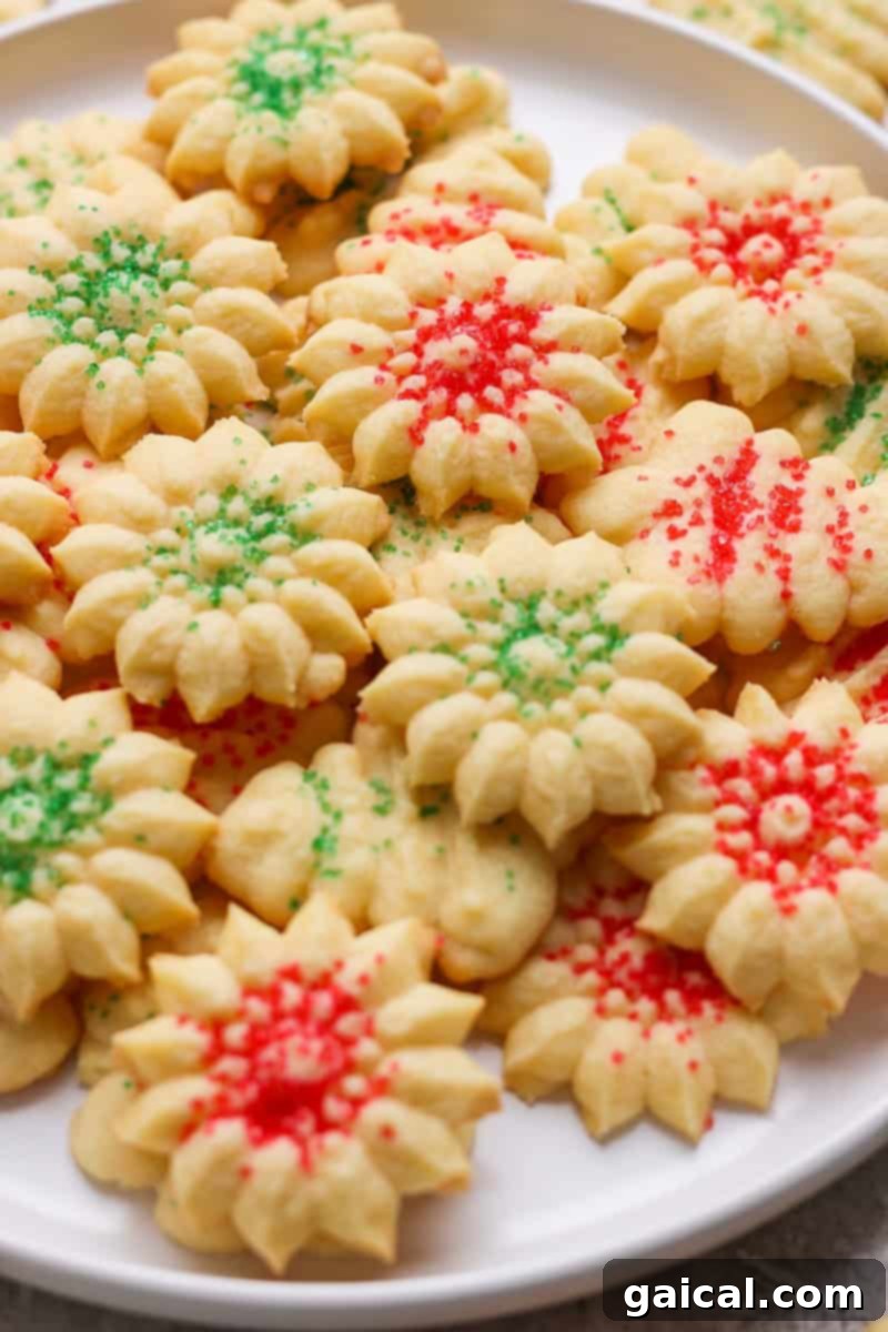 Mabel's Signature Spritz Cookies 7 A charming plate overflowing with flower-shaped Swedish Spritz Cookies, each elegantly decorated with a festive mix of red and green sprinkles, perfect for holiday gatherings.