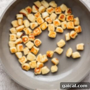 Pan with evenly browned gnocchi pieces on a light surface.