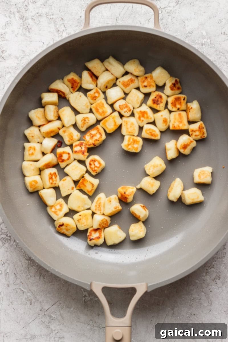 Pillowy Cottage Cheese Gnocchi 5 Pan with evenly browned gnocchi pieces on a light surface.