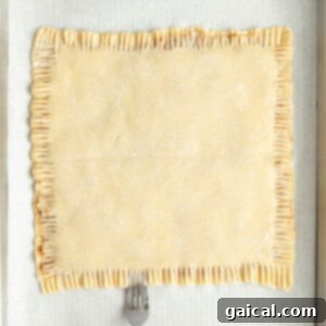 Fueling Frosted Pastries 12 A fork is pressing down the edges of a rectangular pastry on parchment paper in a baking tray.