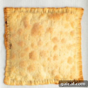 Fueling Frosted Pastries 13 A baked, rectangular pie with crimped edges, small perforations on the top, and a golden-brown crust, placed on parchment paper.