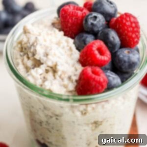 A jar of creamy Cottage Cheese Protein Overnight Oats topped with fresh blueberries and raspberries, ready to be served.