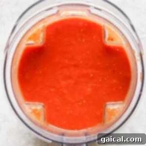 Top view of a blender containing smooth red tomato sauce on a light surface, reminiscent of the perfect partner to grilled cheese.